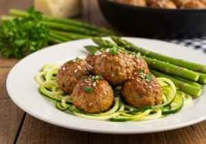 Turkey meatballs with zucchini noodles on white plate garnished with fresh herbs