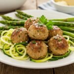Turkey meatballs with zucchini noodles on white plate garnished with fresh herbs